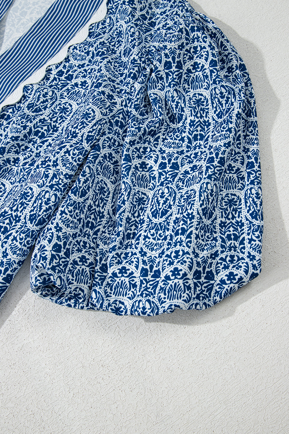 Top de manga abullonada con estampado floral azul y rayas en contraste.