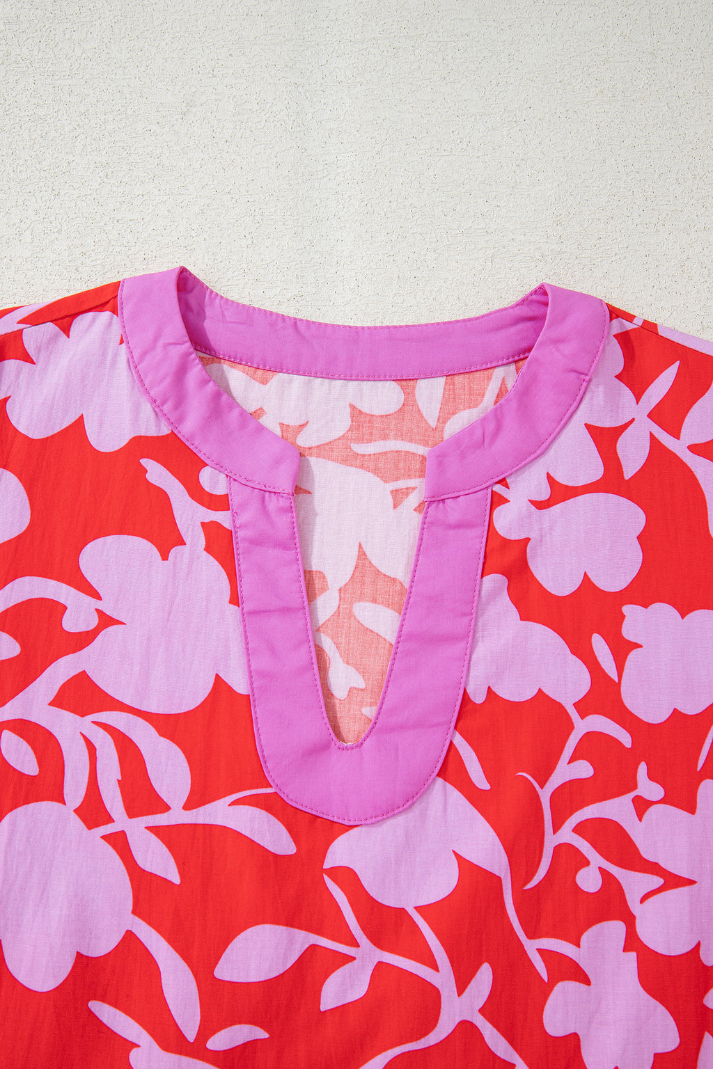Blusa roja con estampado floral, escote en V dividido y mangas tipo brazalete con puños.