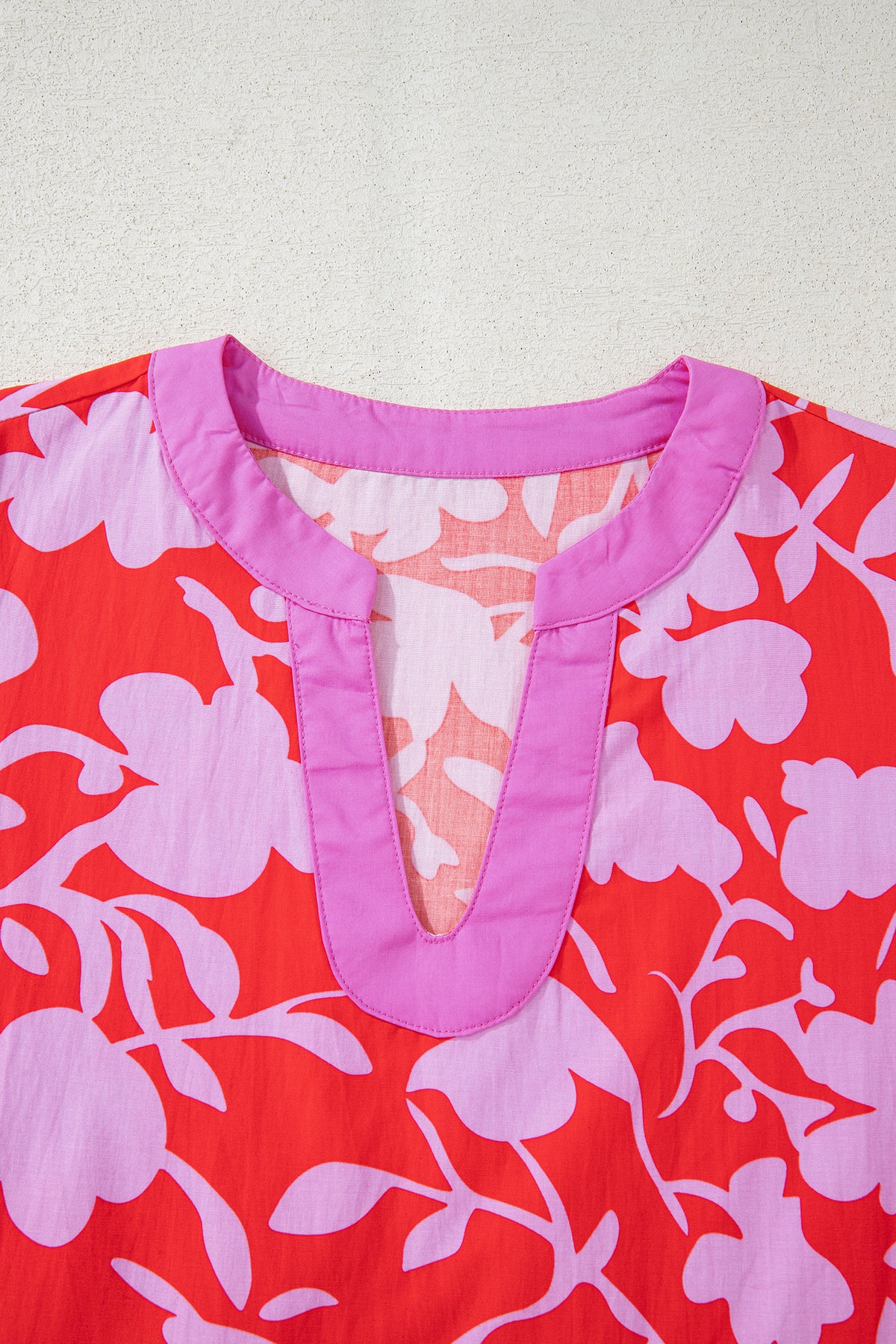 Blusa roja con estampado floral, escote en V dividido y mangas tipo brazalete con puños.