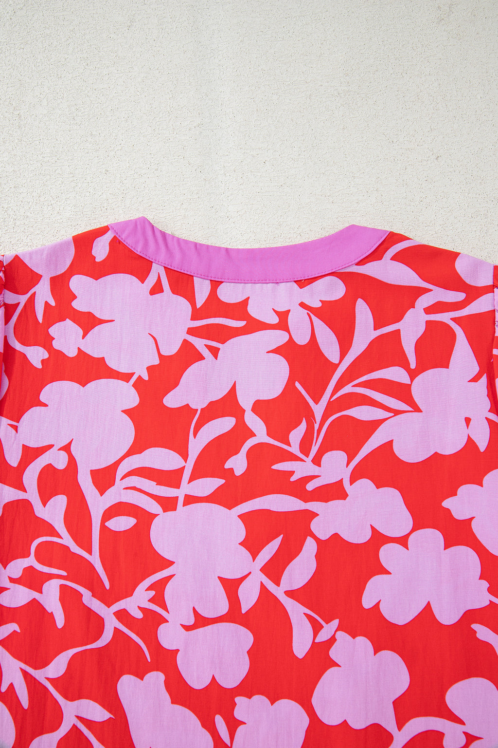 Blusa roja con estampado floral, escote en V dividido y mangas tipo brazalete con puños.