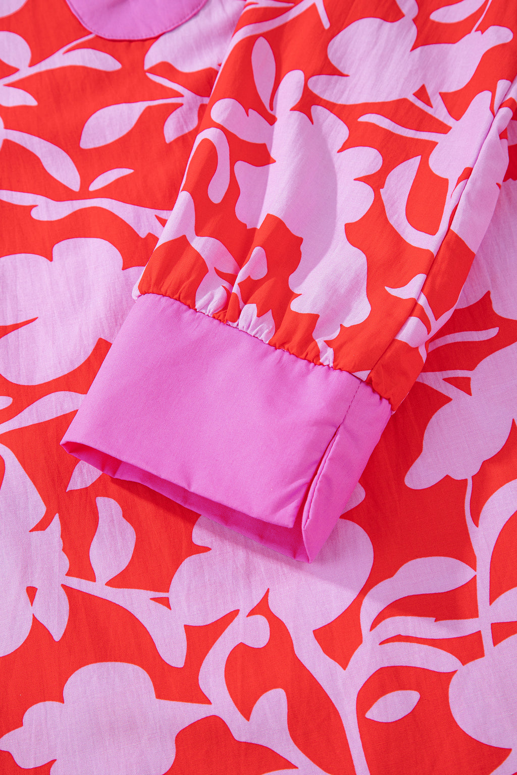 Blusa roja con estampado floral, escote en V dividido y mangas tipo brazalete con puños.