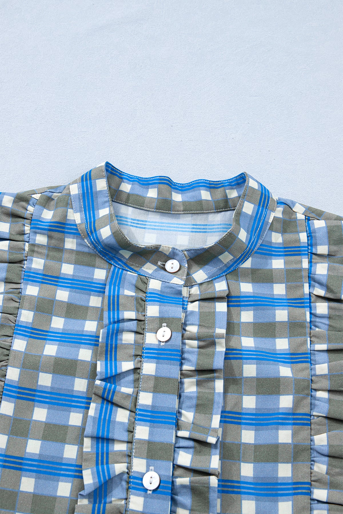 Blusa de manga larga a cuadros azul cielo con detalle de volantes y medio botón.