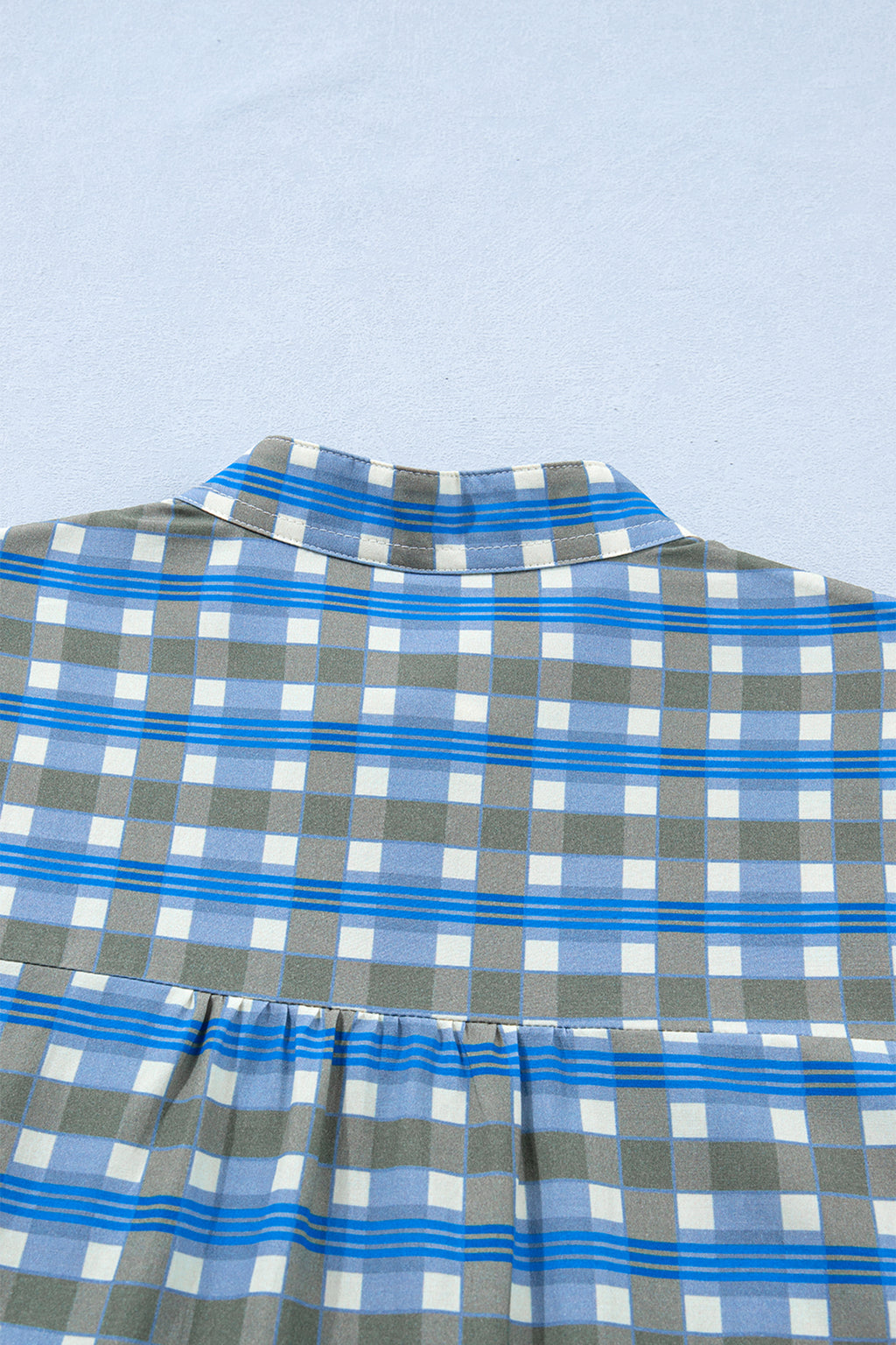 Blusa de manga larga a cuadros azul cielo con detalle de volantes y medio botón.