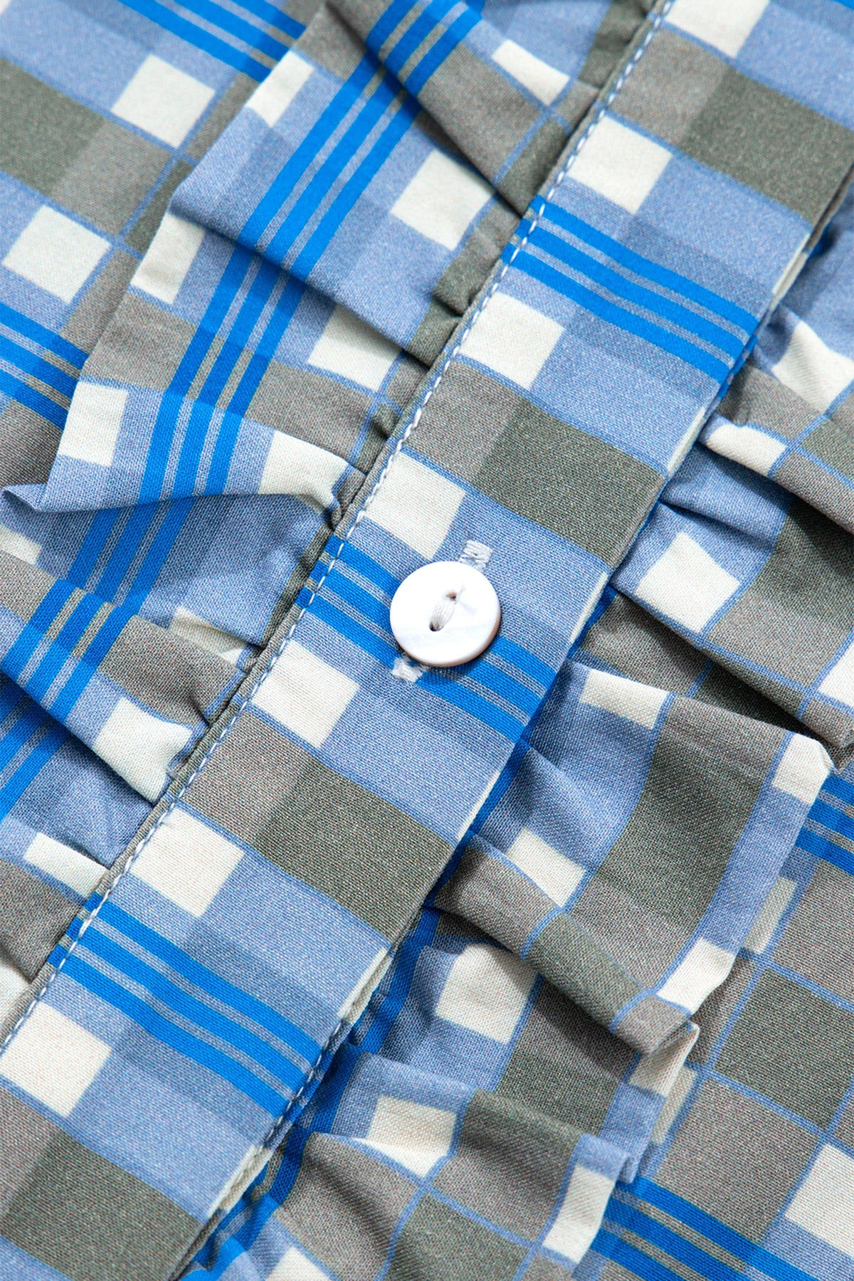 Blusa de manga larga a cuadros azul cielo con detalle de volantes y medio botón.