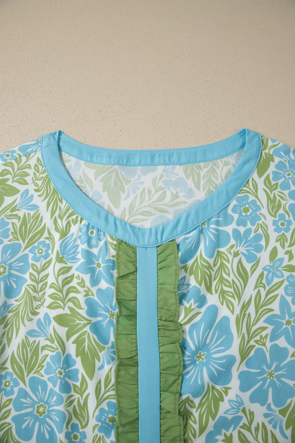 Blusa de manga corta con volantes y ribete de bloques de color, estampado floral azul cielo.