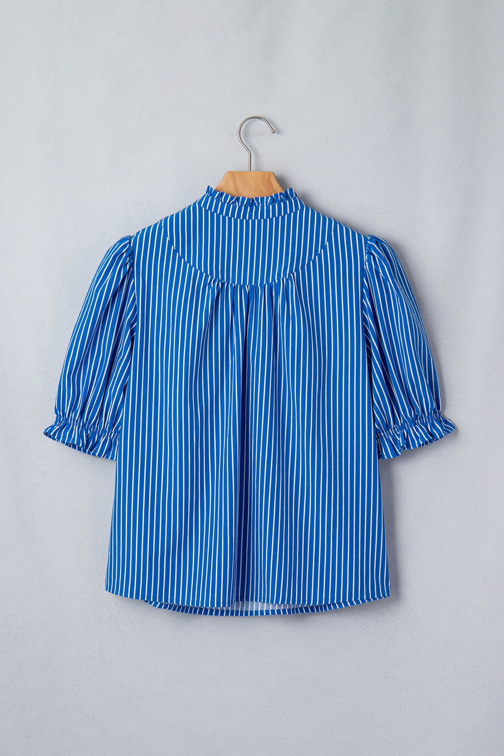 Blusa de manga corta abullonada con volantes y rayas azules, con botones en la parte delantera.