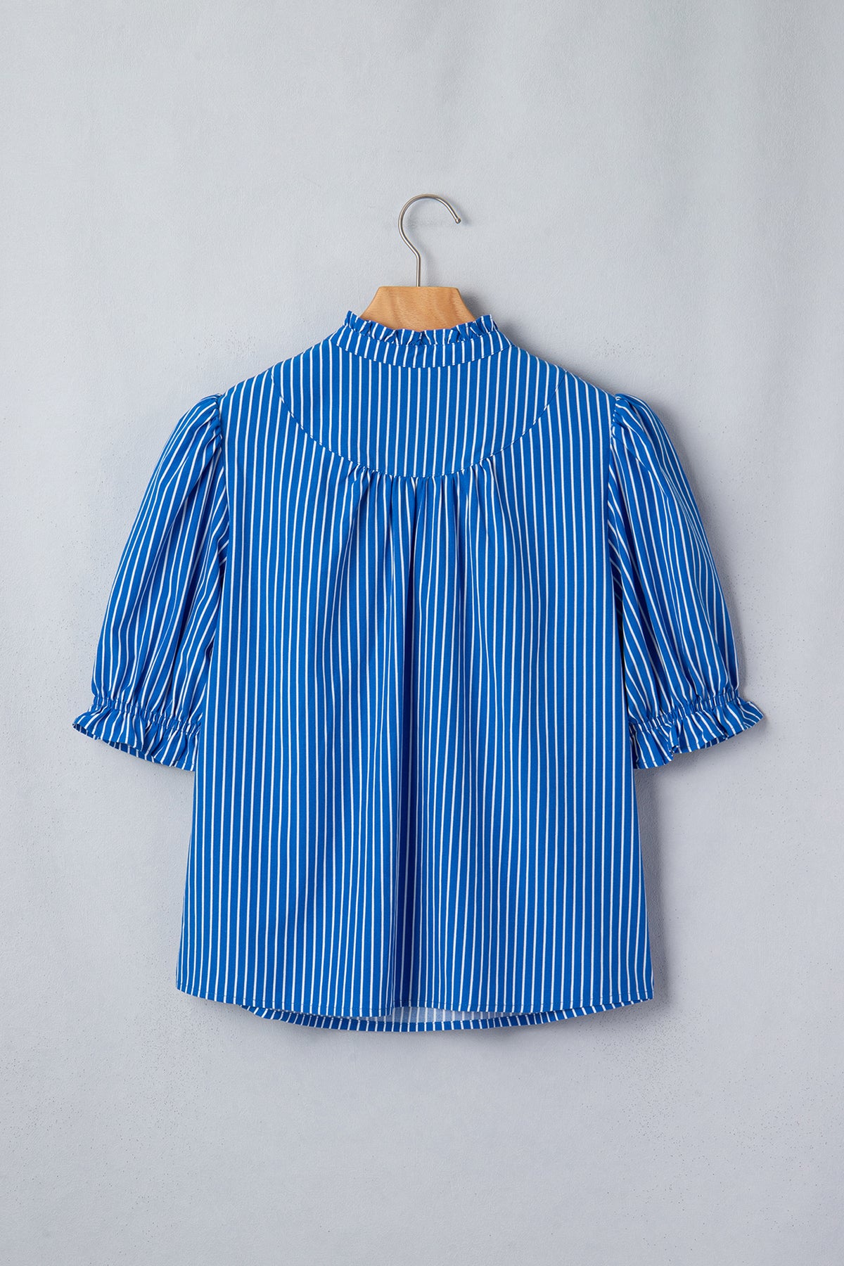Blusa de manga corta abullonada con volantes y rayas azules, con botones en la parte delantera.