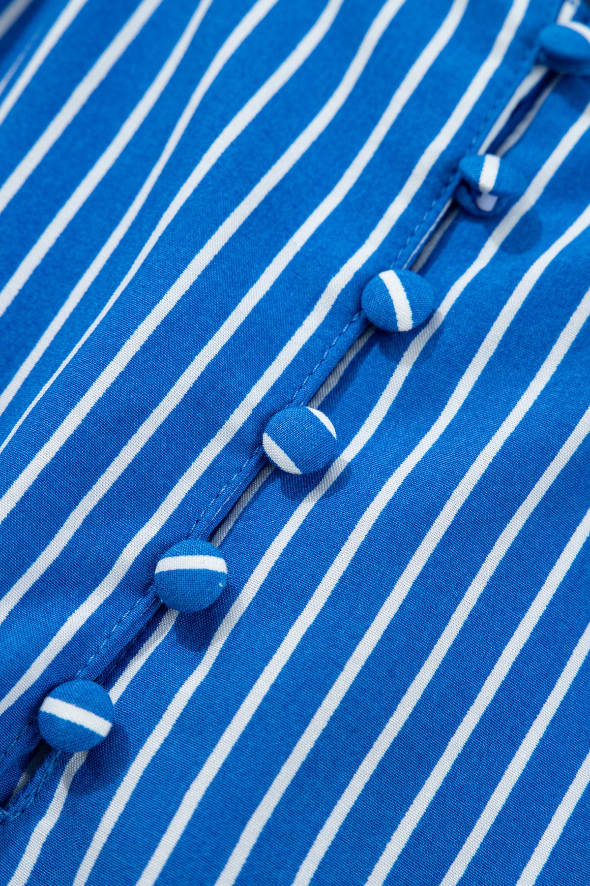 Blusa de manga corta abullonada con volantes y rayas azules, con botones en la parte delantera.