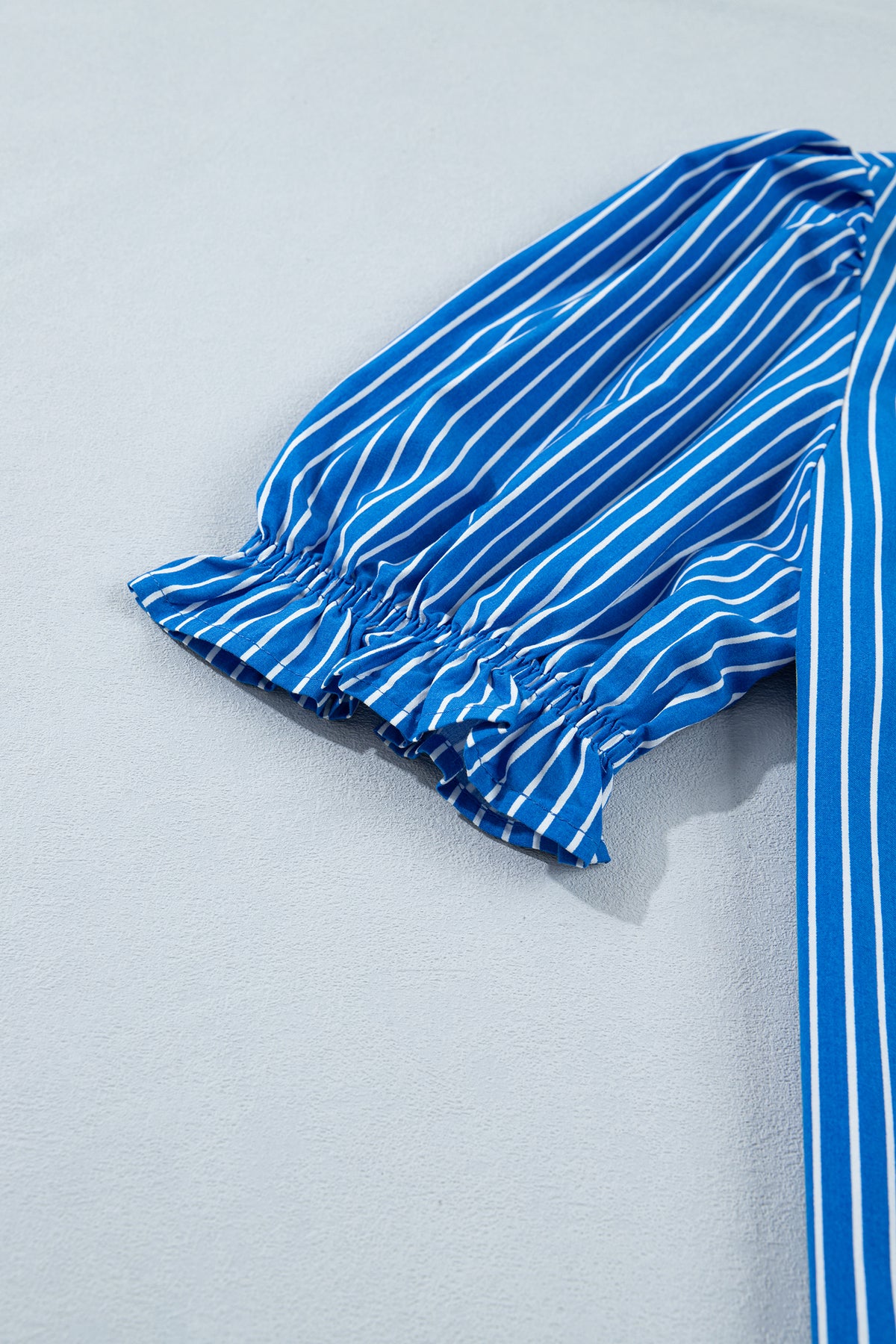 Blusa de manga corta abullonada con volantes y rayas azules, con botones en la parte delantera.