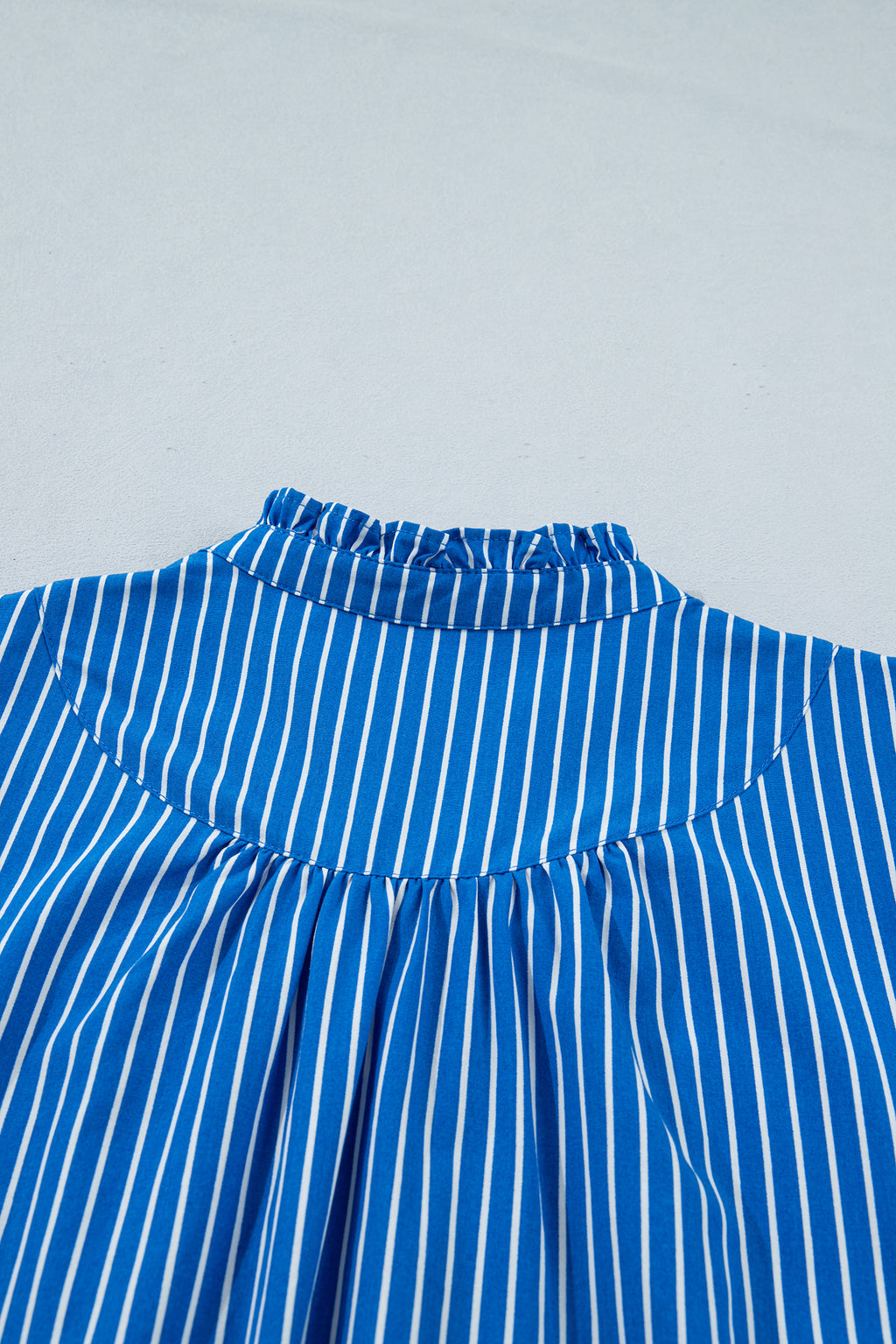 Blusa de manga corta abullonada con volantes y rayas azules, con botones en la parte delantera.