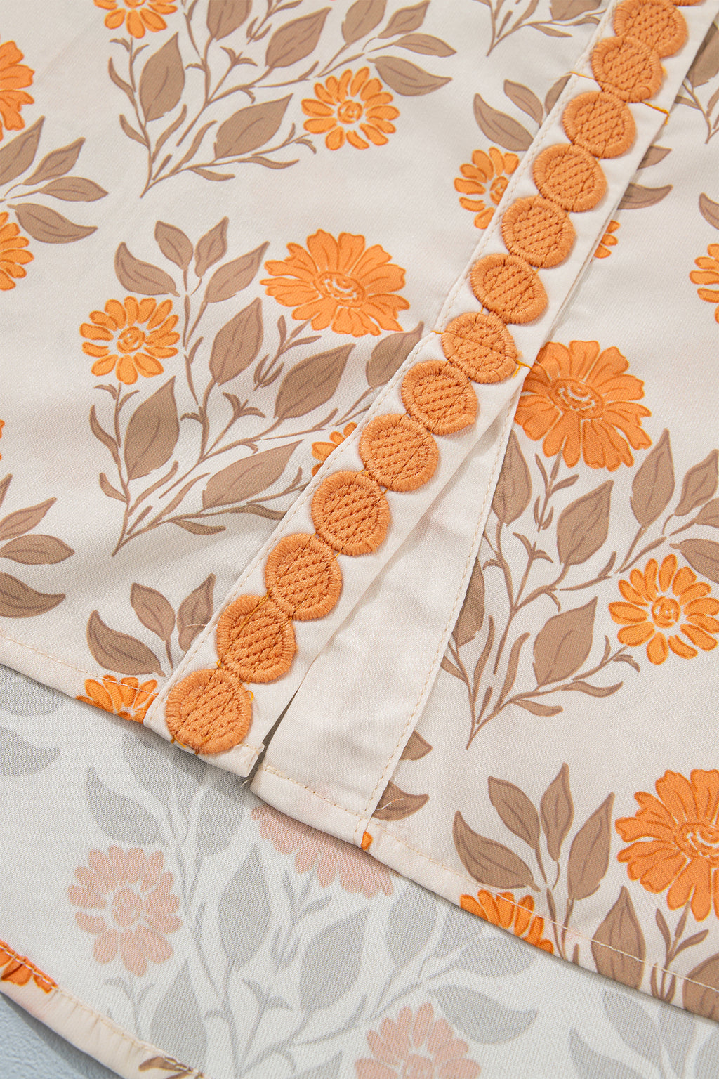 Blusa de manga larga con cuello en V y estampado floral naranja con detalles en contraste.