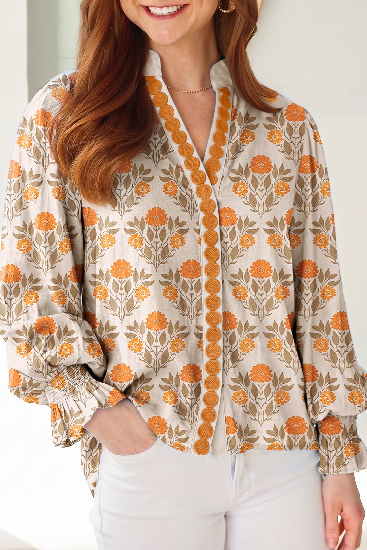 Blusa de manga larga con cuello en V y estampado floral naranja con detalles en contraste.