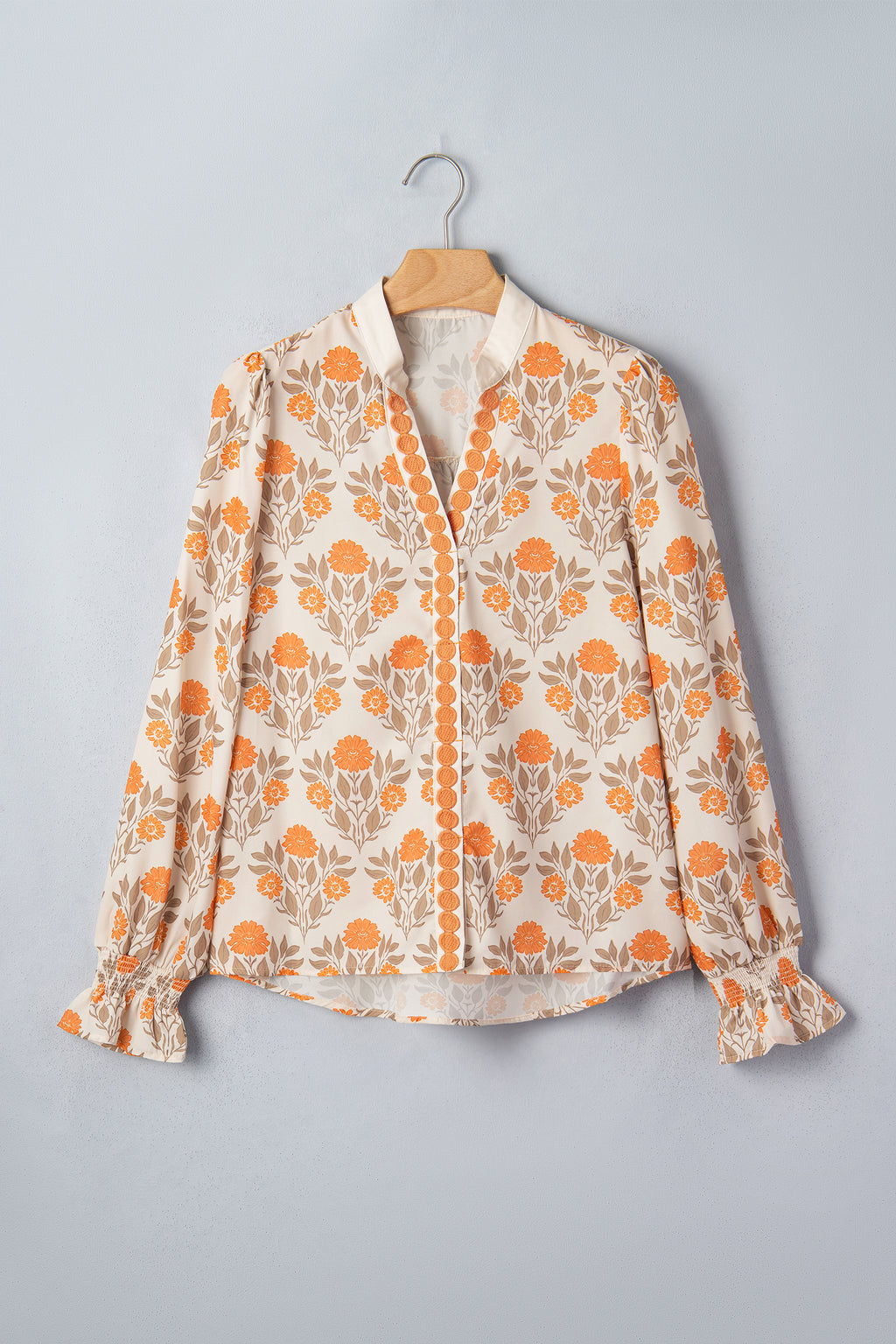 Blusa de manga larga con cuello en V y estampado floral naranja con detalles en contraste.