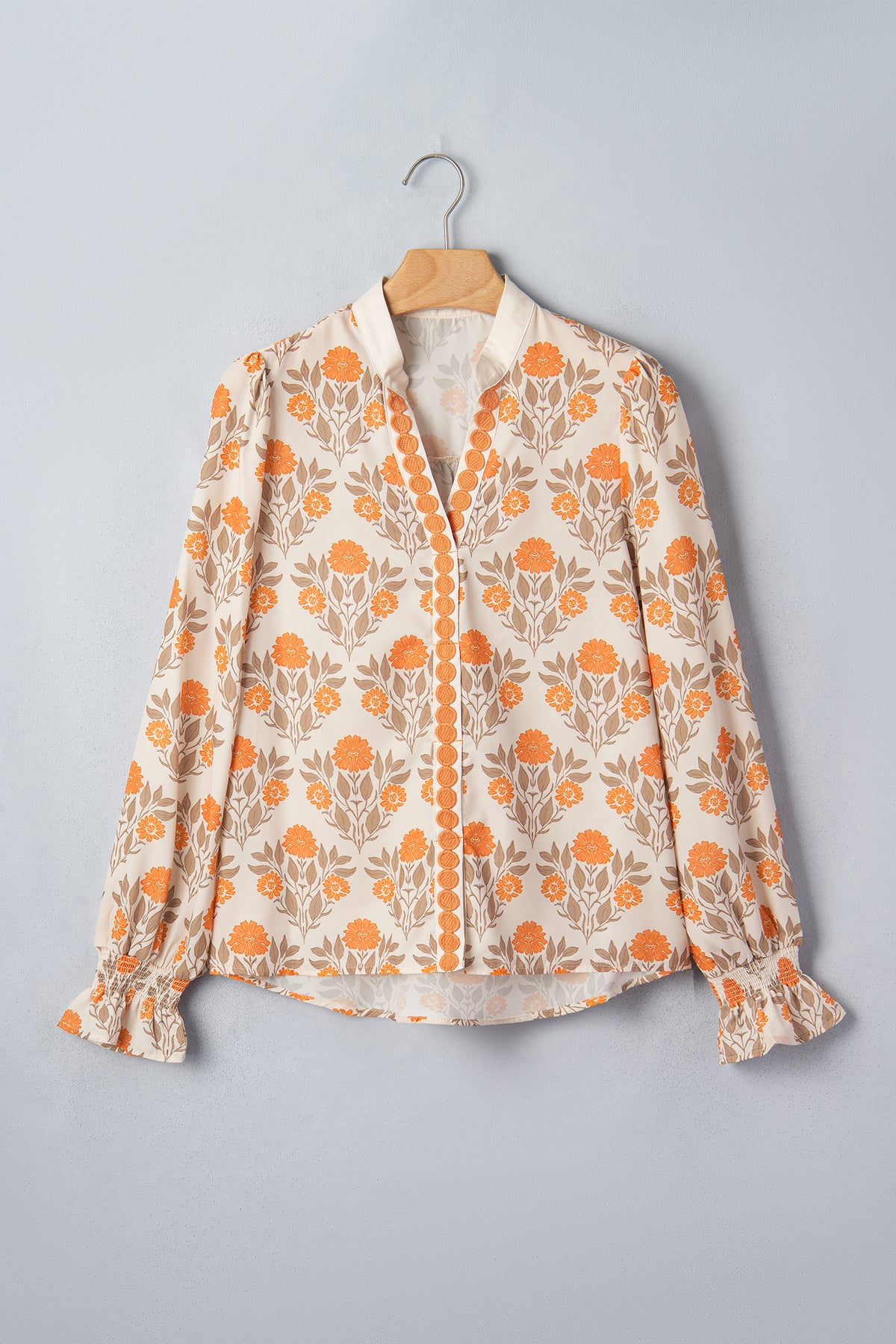 Blusa de manga larga con cuello en V y estampado floral naranja con detalles en contraste.