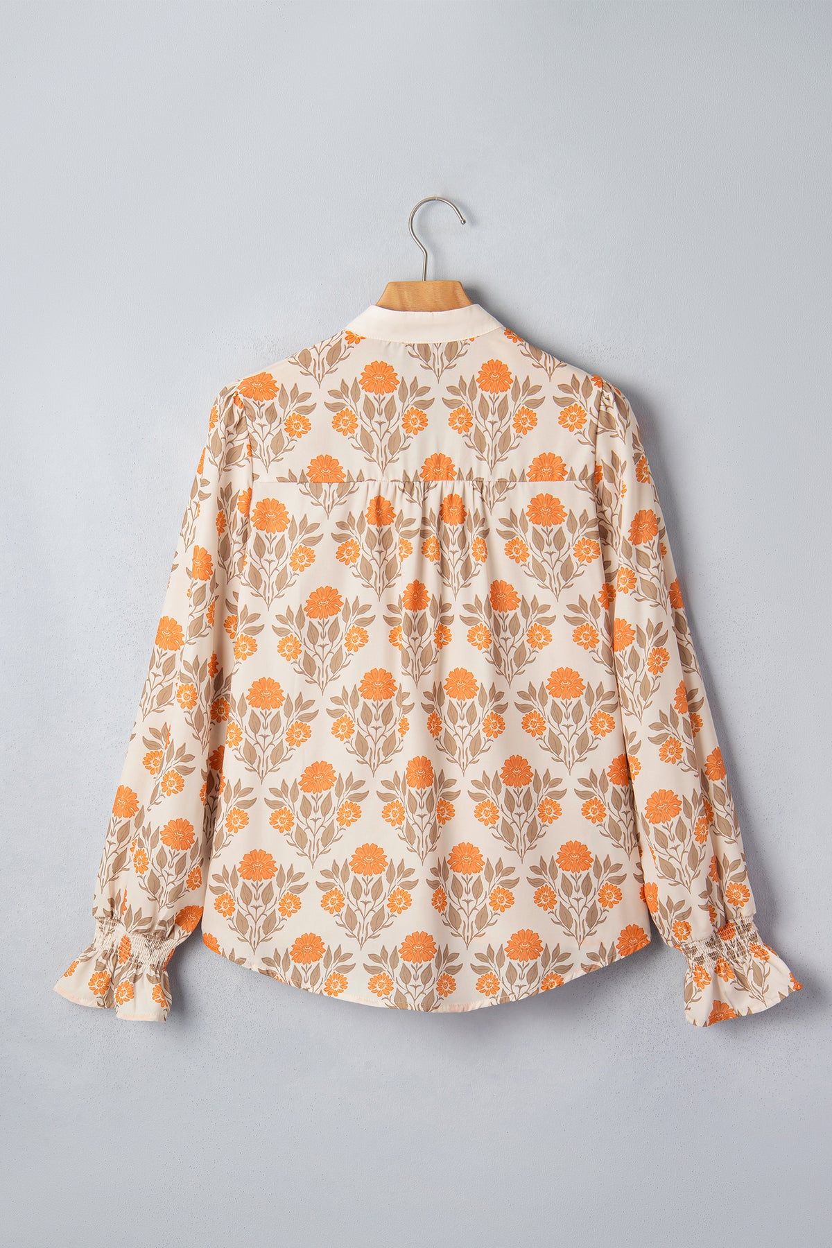 Blusa de manga larga con cuello en V y estampado floral naranja con detalles en contraste.