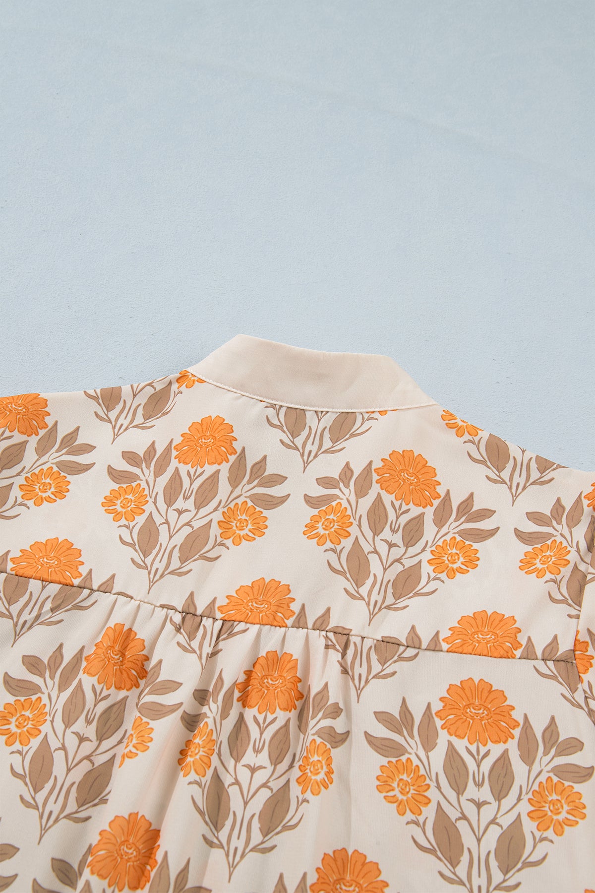 Blusa de manga larga con cuello en V y estampado floral naranja con detalles en contraste.