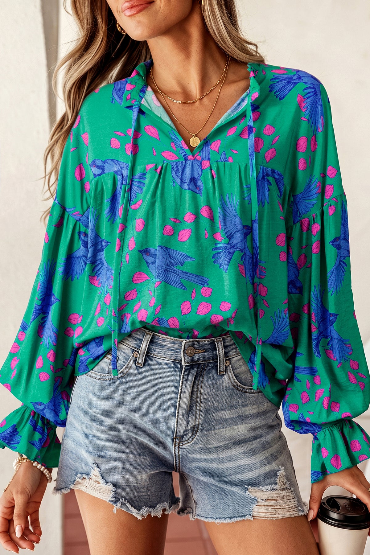 Blusa verde con estampado abstracto, escote en V y mangas abullonadas con volantes.