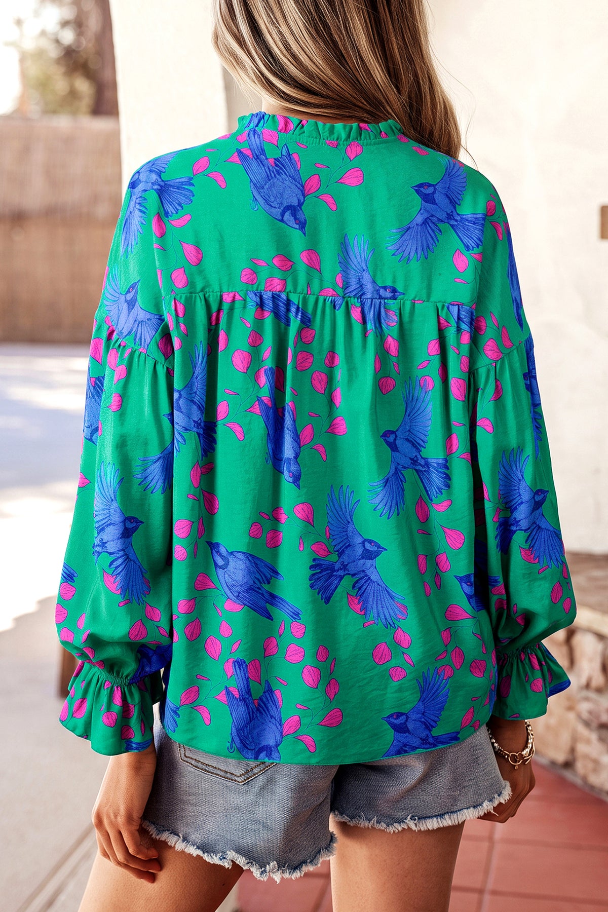 Blusa verde con estampado abstracto, escote en V y mangas abullonadas con volantes.