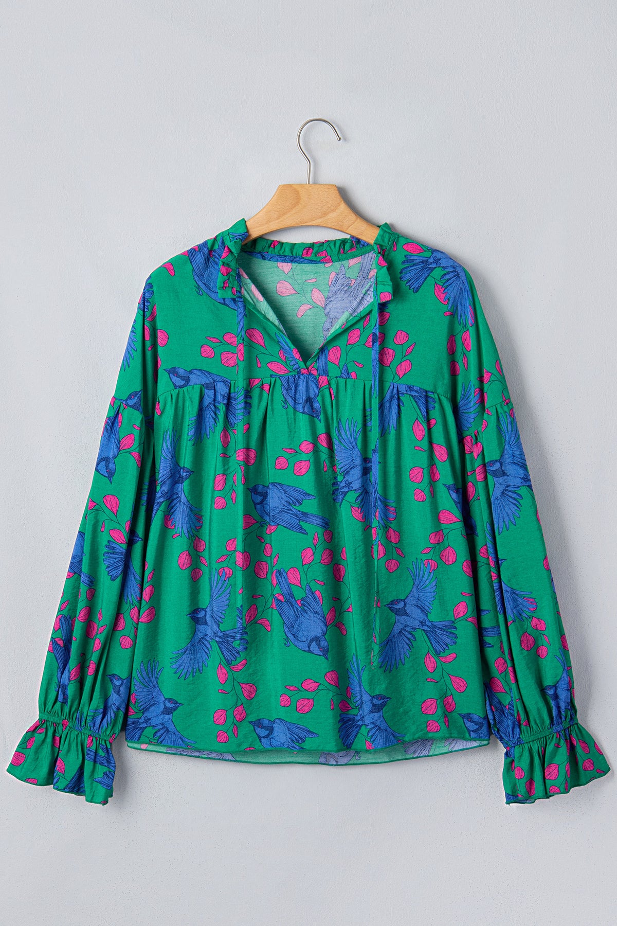Blusa verde con estampado abstracto, escote en V y mangas abullonadas con volantes.