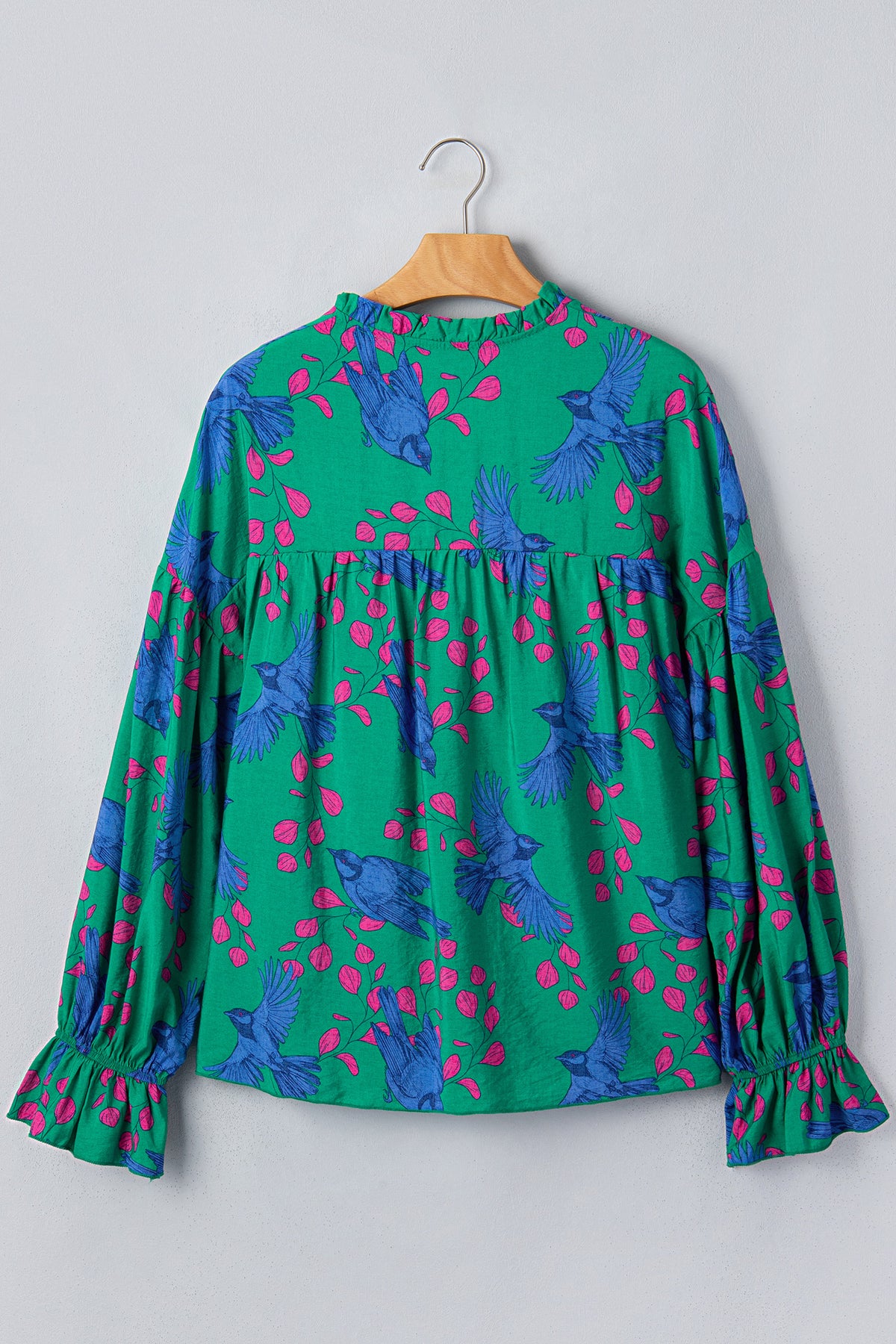 Blusa verde con estampado abstracto, escote en V y mangas abullonadas con volantes.