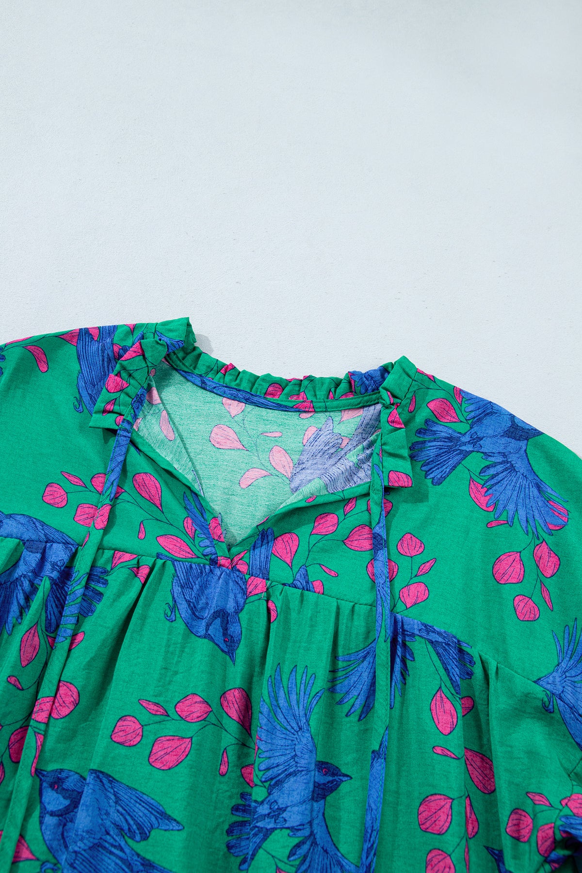 Blusa verde con estampado abstracto, escote en V y mangas abullonadas con volantes.