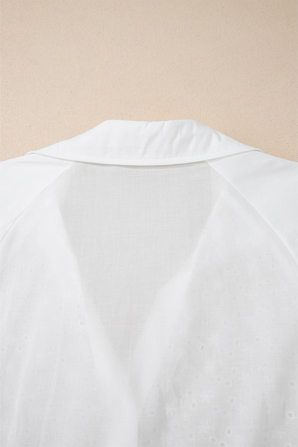 Camisa blanca con mangas abullonadas, bordado floral y detalles de ojales.