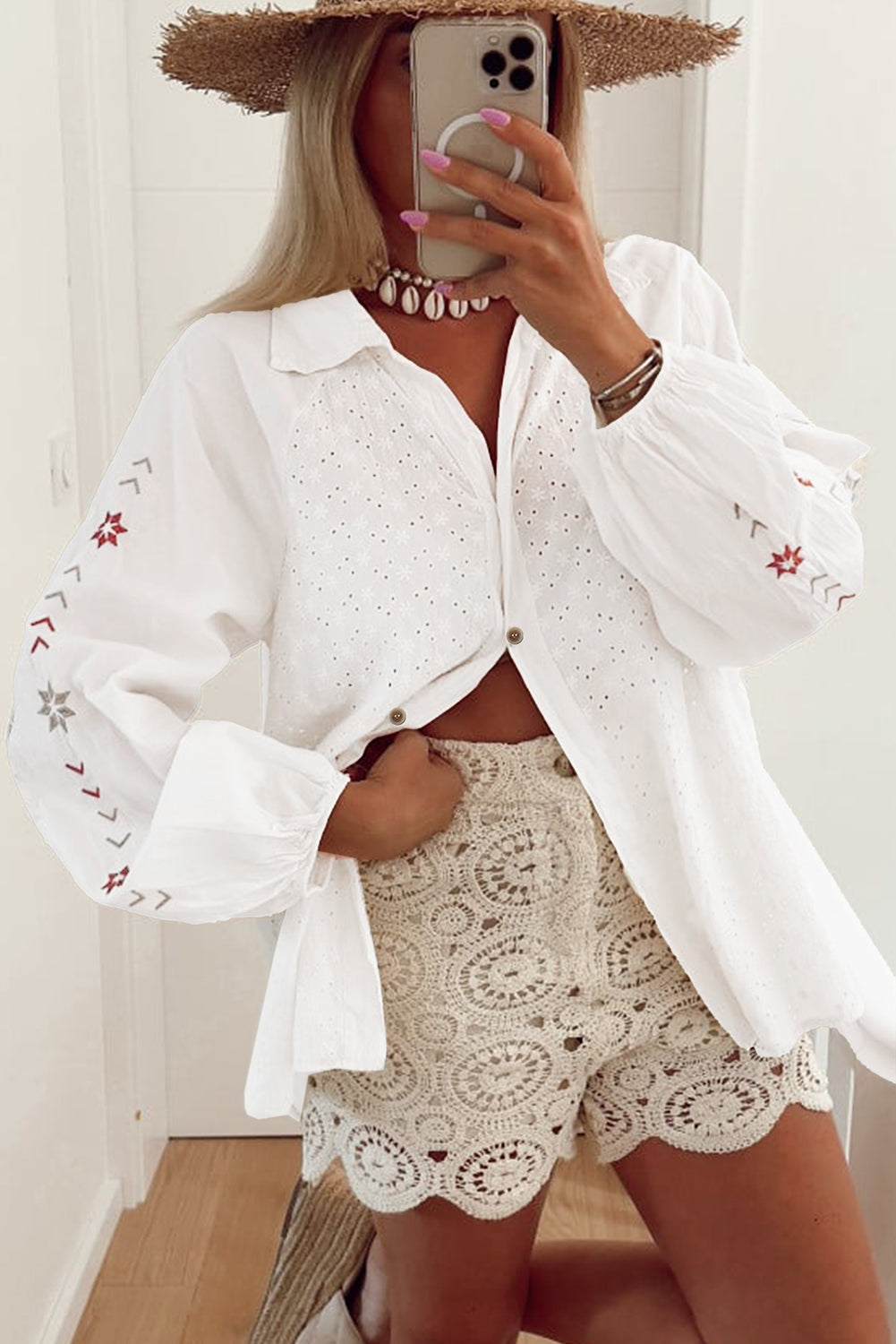 Camisa blanca con mangas abullonadas, bordado floral y detalles de ojales.