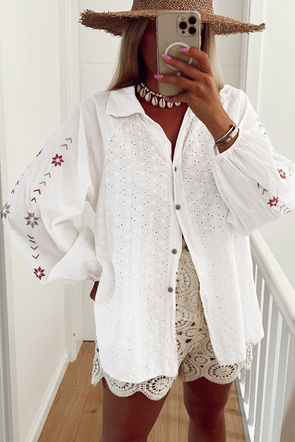 Camisa blanca con mangas abullonadas, bordado floral y detalles de ojales.