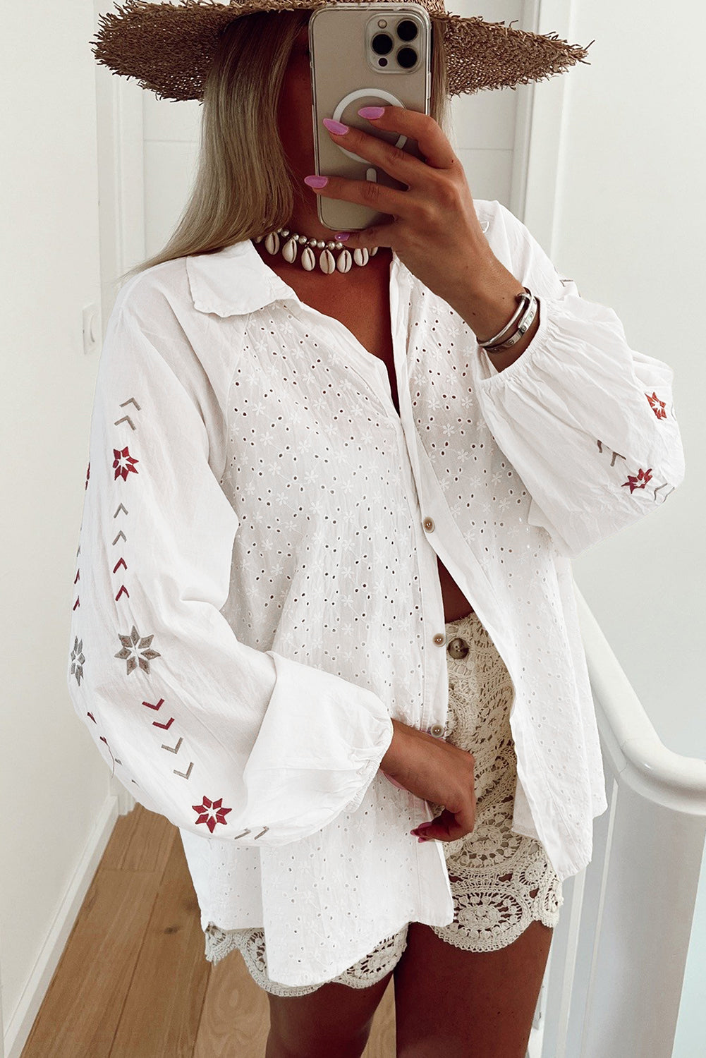 Camisa blanca con mangas abullonadas, bordado floral y detalles de ojales.