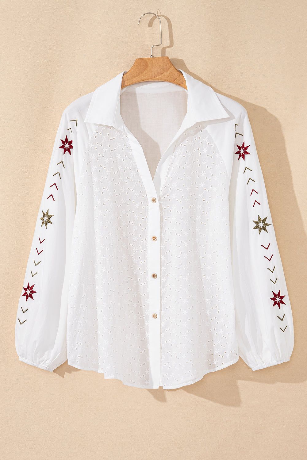 Camisa blanca con mangas abullonadas, bordado floral y detalles de ojales.