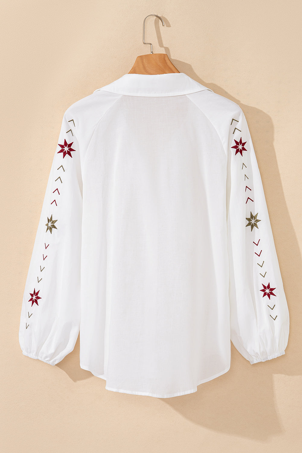 Camisa blanca con mangas abullonadas, bordado floral y detalles de ojales.