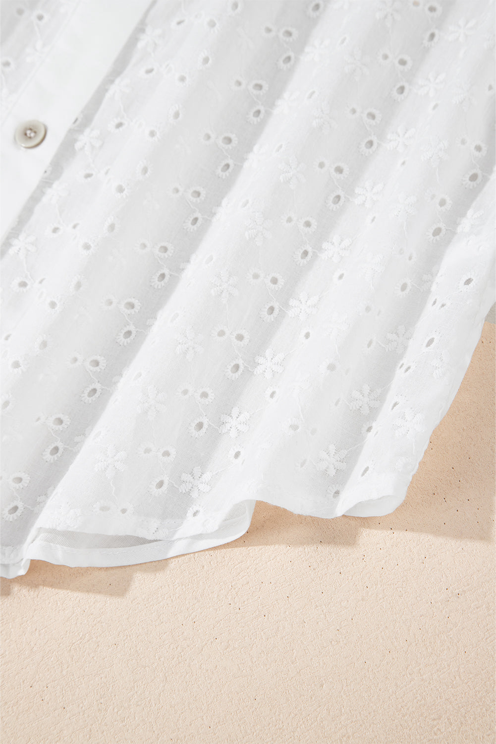 Camisa blanca con mangas abullonadas, bordado floral y detalles de ojales.