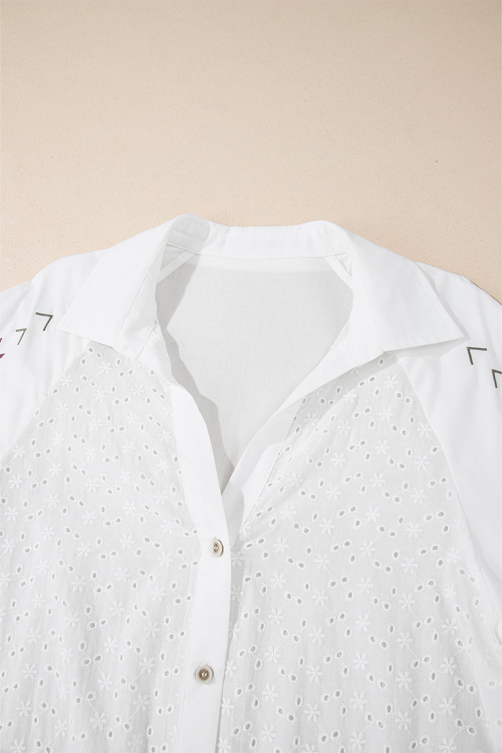 Camisa blanca con mangas abullonadas, bordado floral y detalles de ojales.