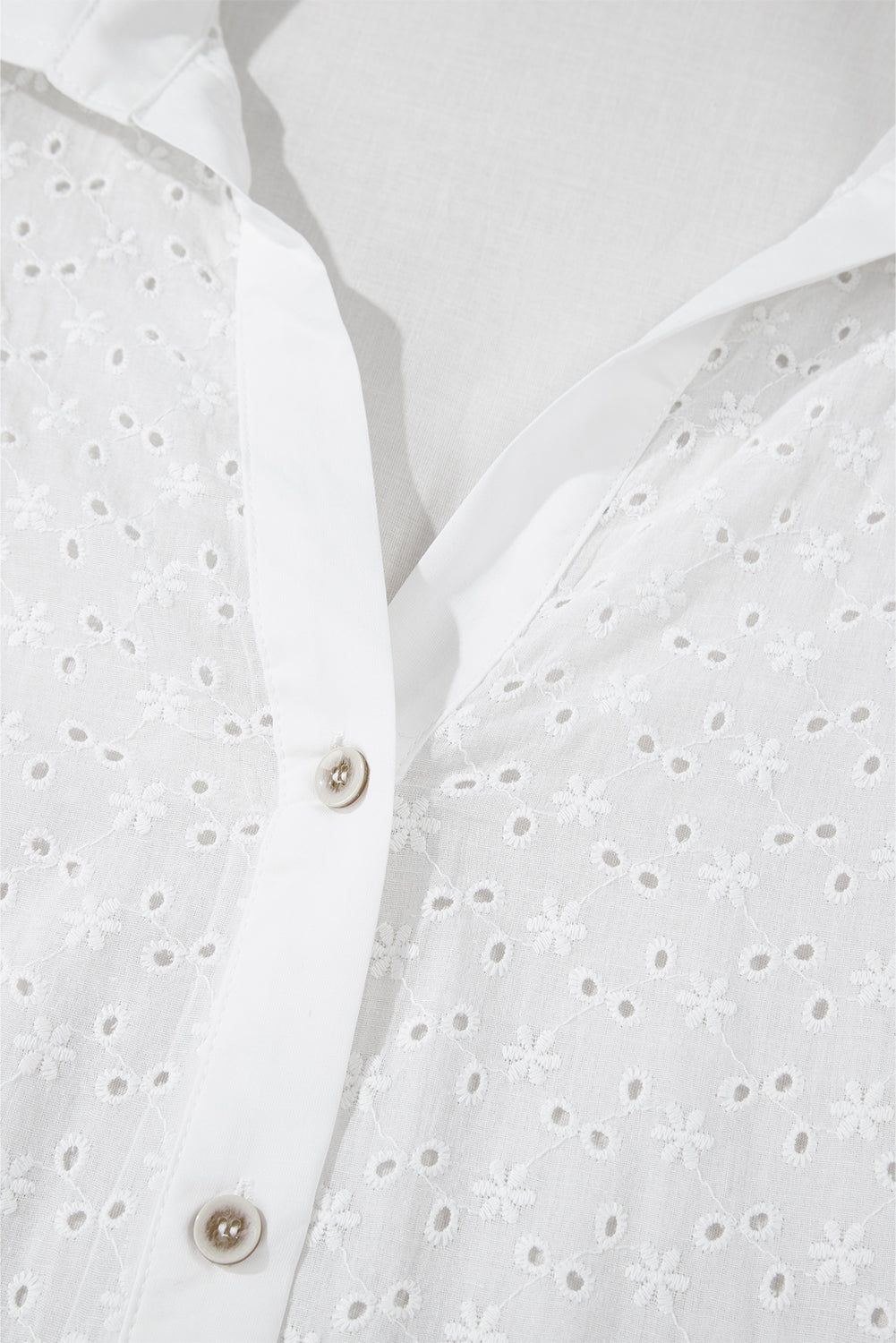 Camisa blanca con mangas abullonadas, bordado floral y detalles de ojales.