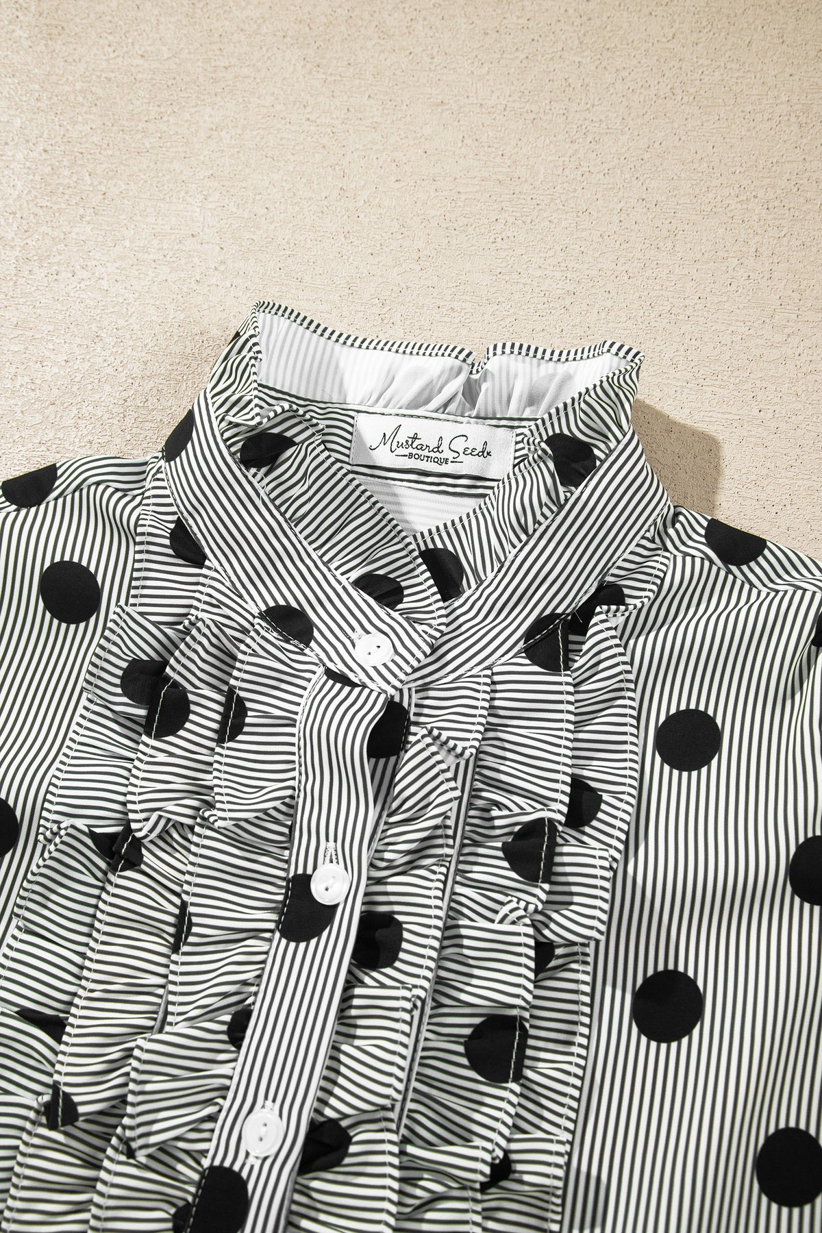 Camisa de manga tres cuartos con cuello alto, cuello alto y estampado de rayas y lunares rojos intensos.