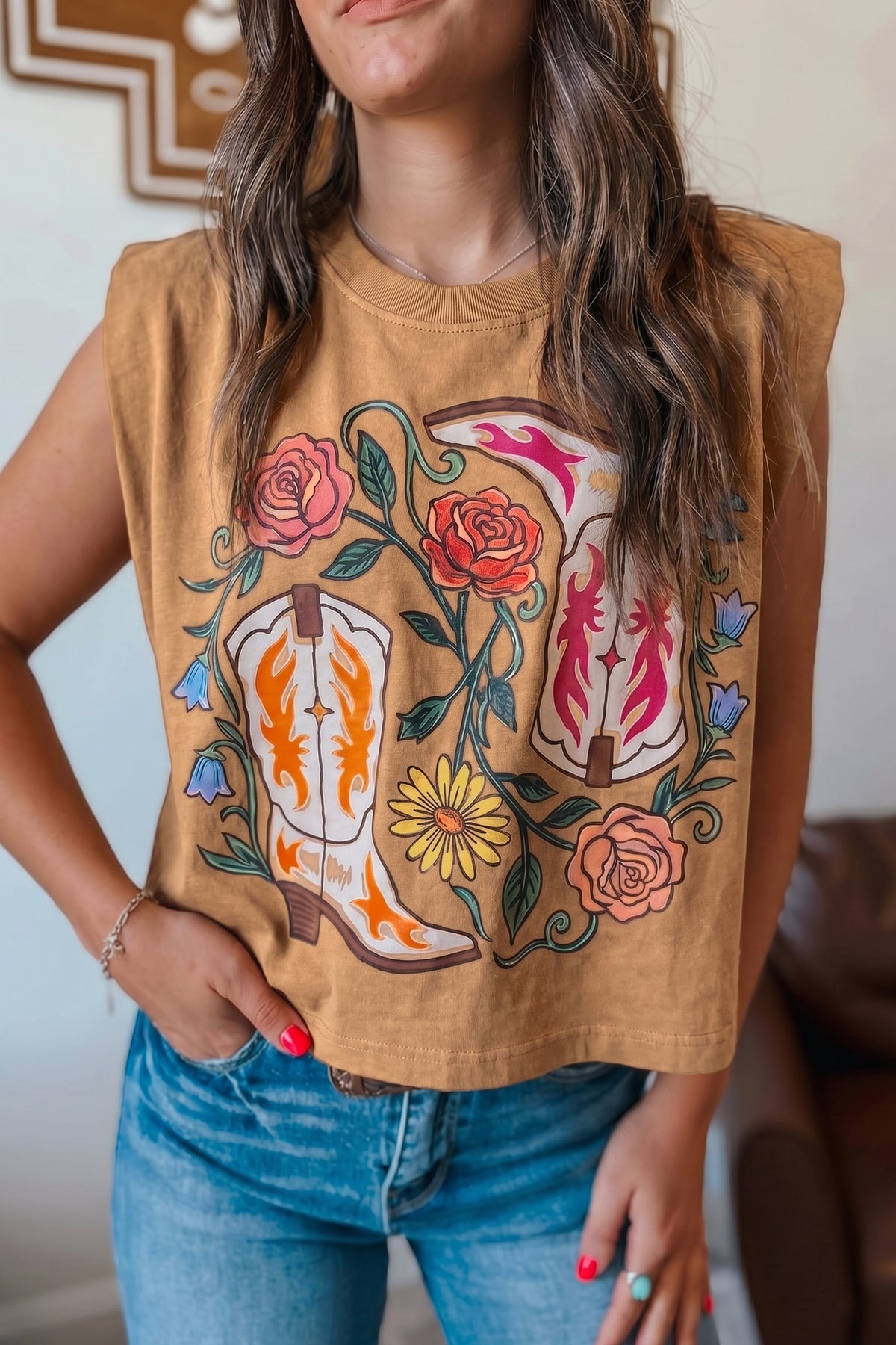 Camiseta sin mangas holgada con estampado floral y botas vaqueras color camel.