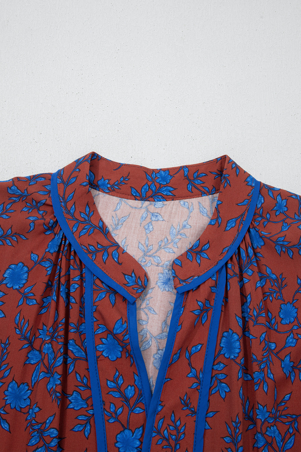 Vestido holgado marrón con mangas tres cuartos abullonadas y volantes florales.