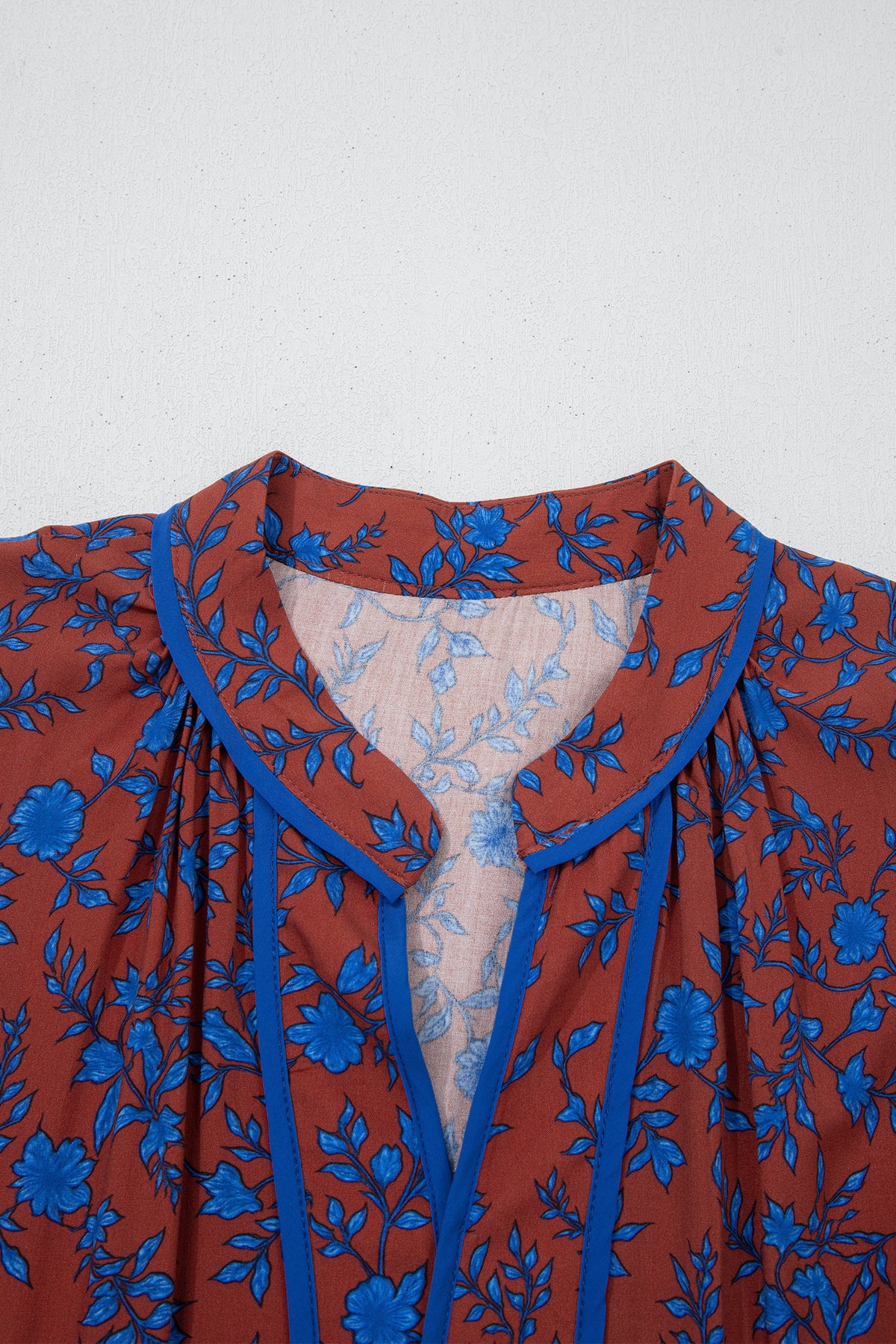 Vestido holgado marrón con mangas tres cuartos abullonadas y volantes florales.