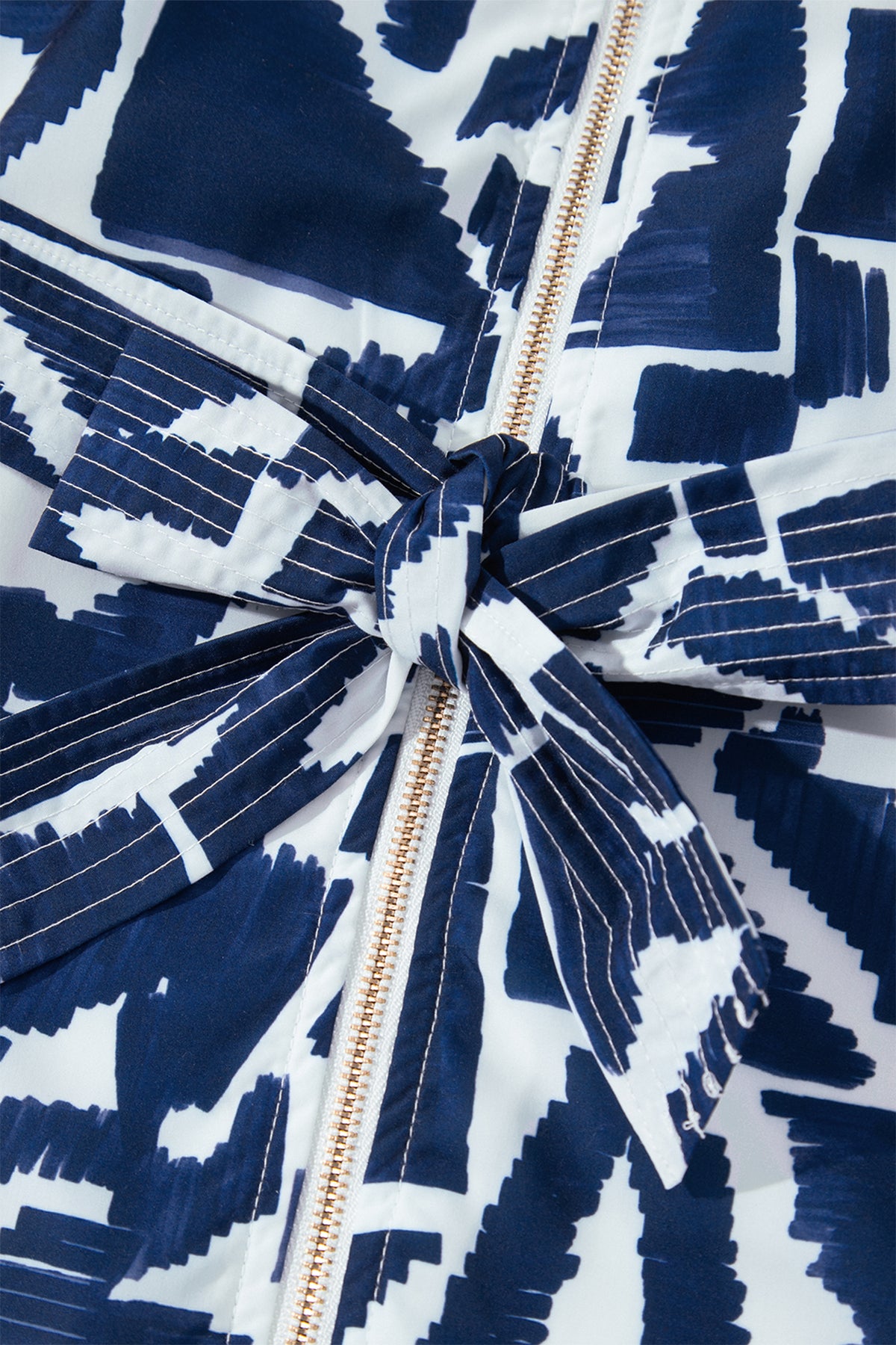 Vestido recto azul con estampado geométrico abstracto, cremallera frontal y lazo en la cintura.
