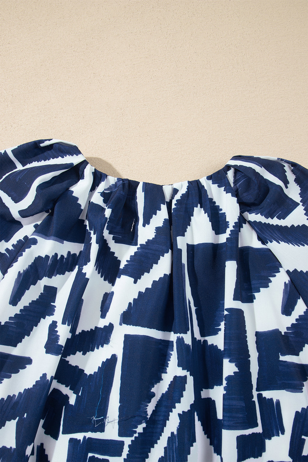 Vestido recto azul con estampado geométrico abstracto, cremallera frontal y lazo en la cintura.