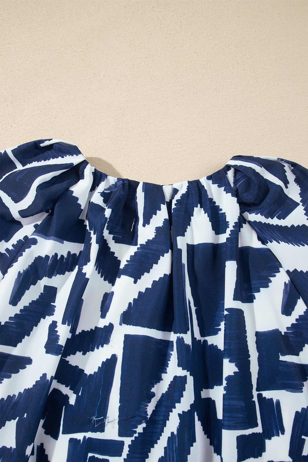 Vestido recto azul con estampado geométrico abstracto, cremallera frontal y lazo en la cintura.