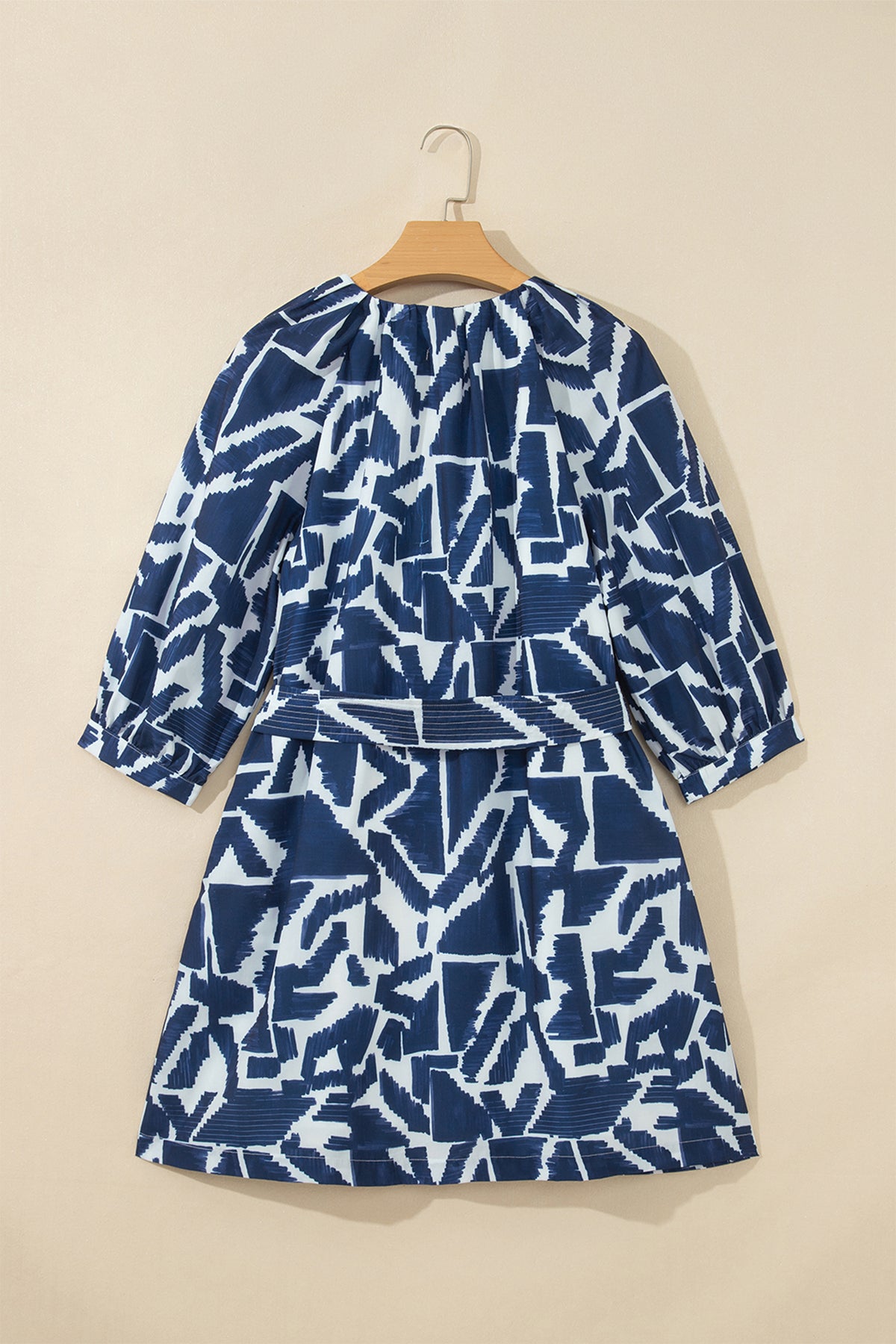 Vestido recto azul con estampado geométrico abstracto, cremallera frontal y lazo en la cintura.