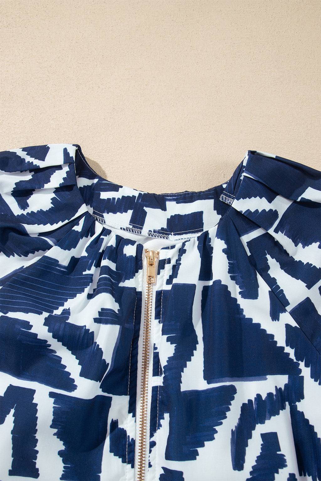 Vestido recto azul con estampado geométrico abstracto, cremallera frontal y lazo en la cintura.