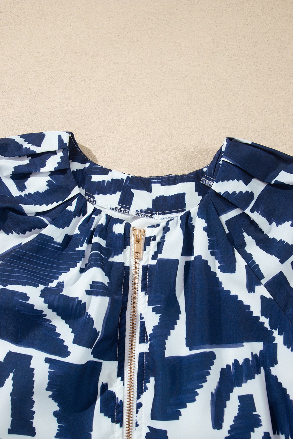 Vestido recto azul con estampado geométrico abstracto, cremallera frontal y lazo en la cintura.