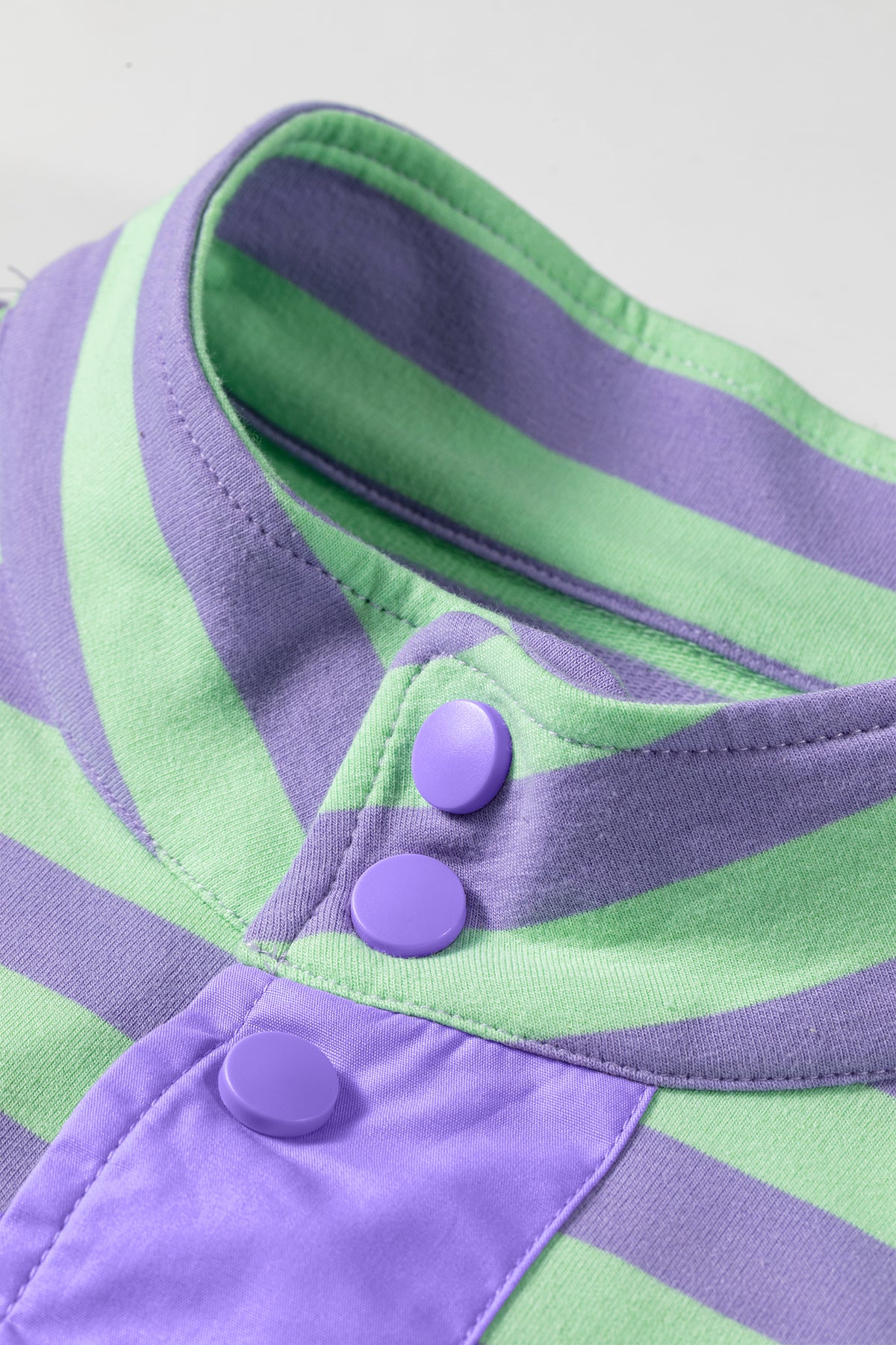 Conjunto de 2 piezas: top de manga larga con medio botón y rayas moradas, y shorts combinables.