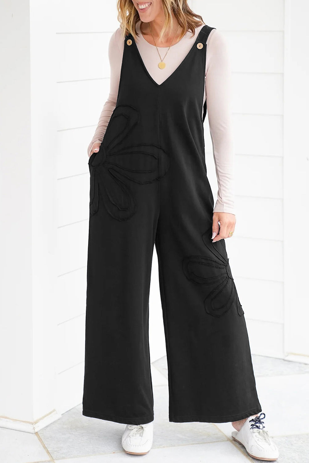 Mono holgado negro liso con costuras sin rematar y parches de flores grandes.