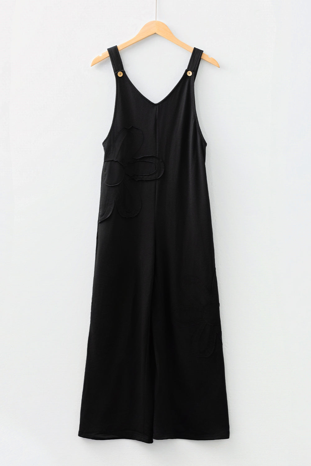 Mono holgado negro liso con costuras sin rematar y parches de flores grandes.