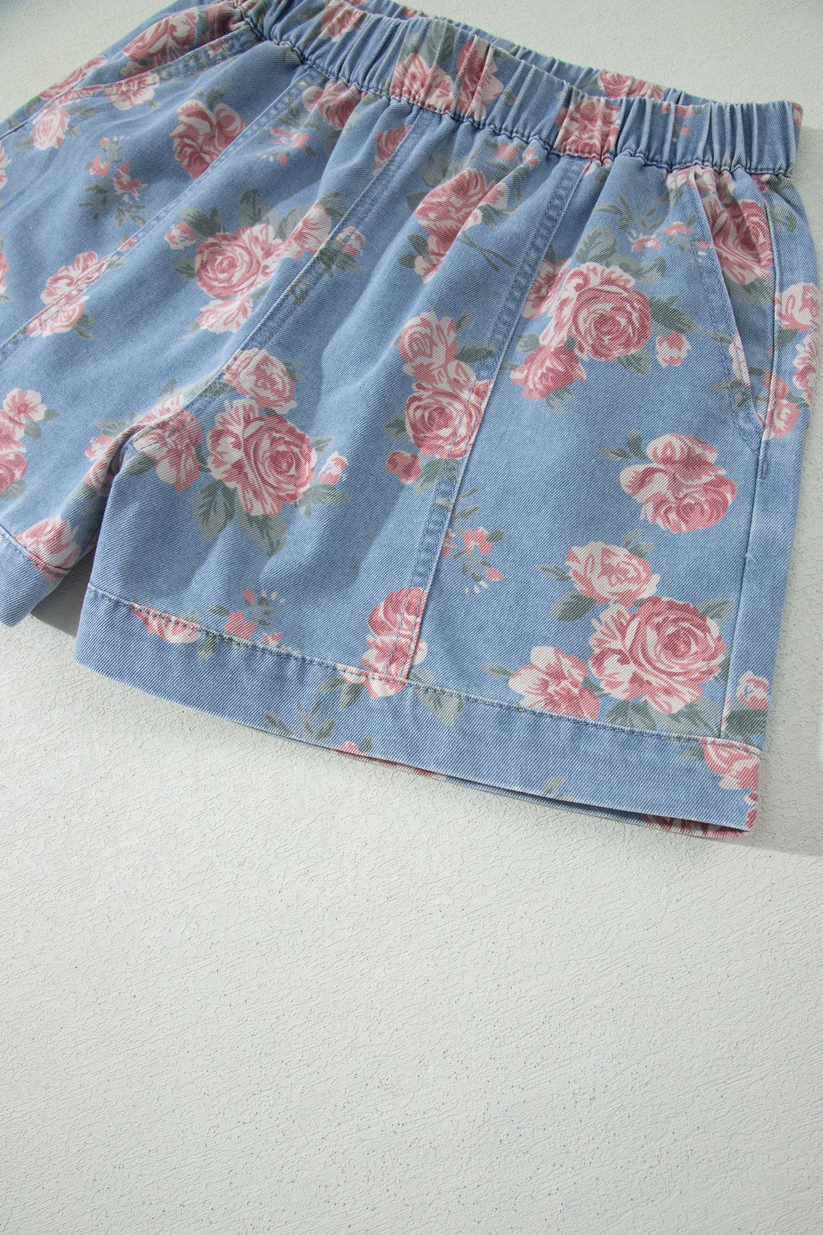 Conjunto de 2 piezas: top de manga corta de mezclilla azul cielo con estampado floral y shorts holgados.